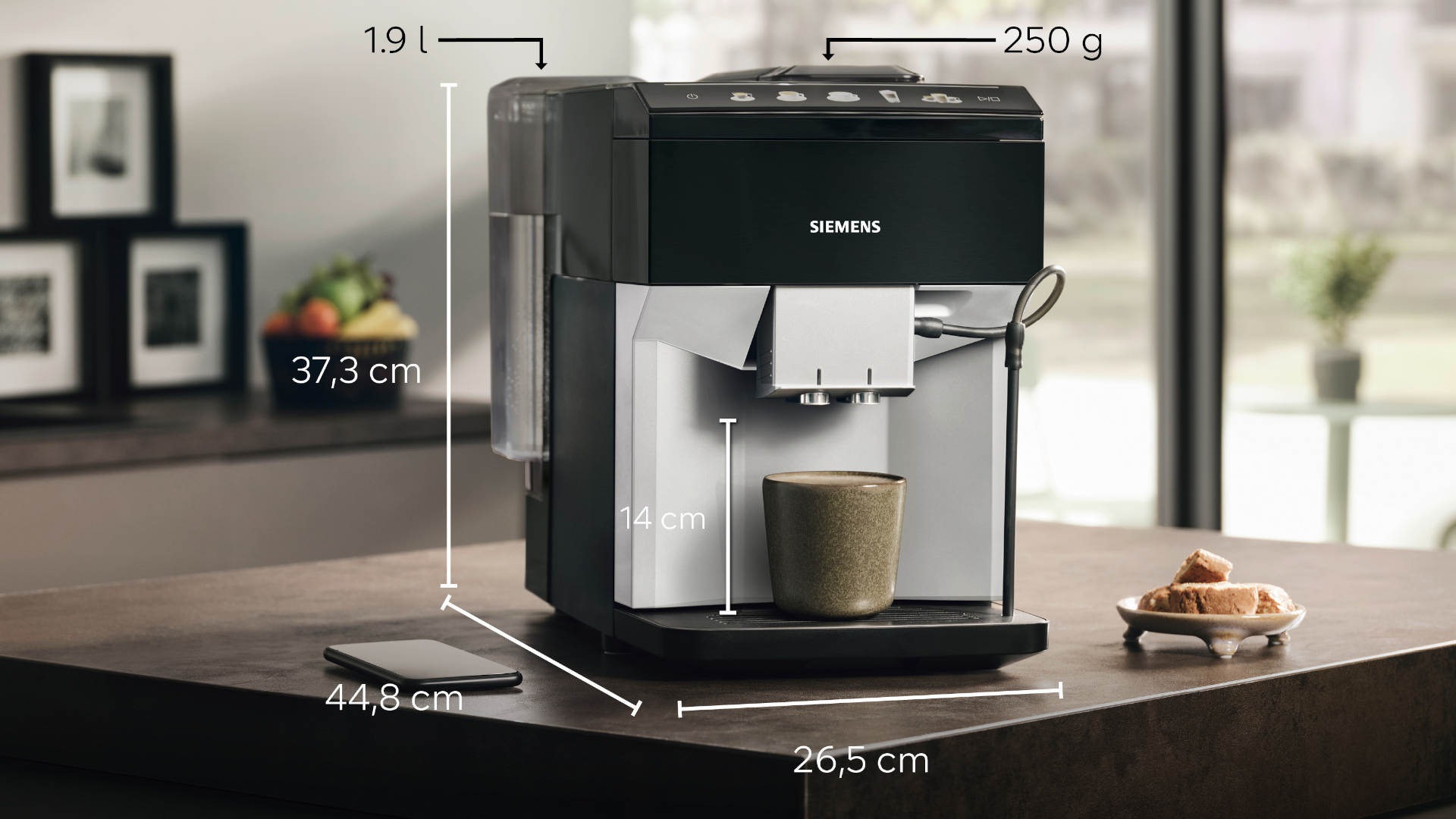 Zwarte Siemens koffiemachine met kopje, smartphone en koekjes op een donker aanrecht. Afmetingen zijn aangegeven met pijlen.