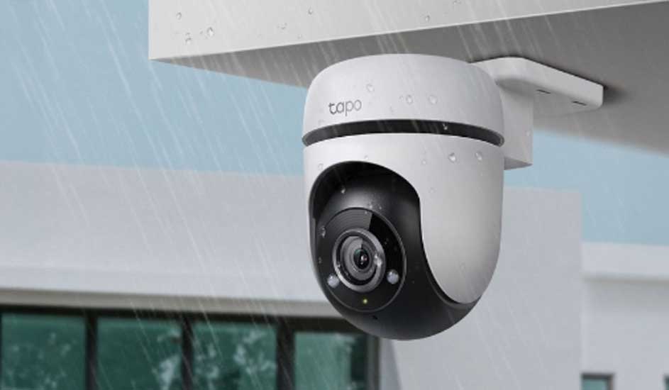 Een witte Tapo beveiligingscamera is buiten aan het plafond bevestigd en werkt in de regen. Het ontwerp is modern en weerbestendig.