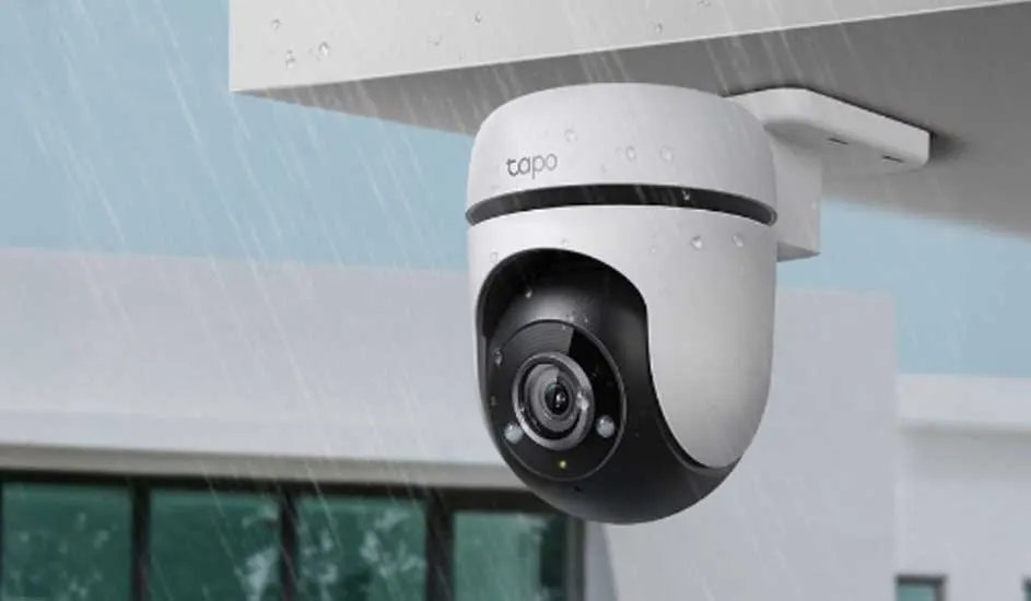 Een witte Tapo beveiligingscamera is buiten aan het plafond bevestigd en werkt in de regen. Het ontwerp is modern en weerbestendig.