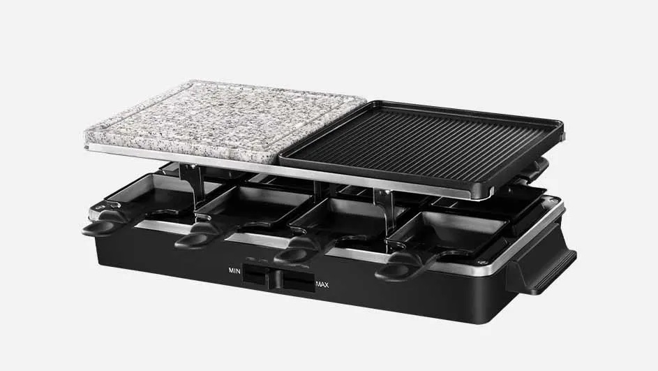 Een raclette-apparaat met een zwarte basis, pannetjes en een grillplaat en stenen plaat aan de bovenkant.