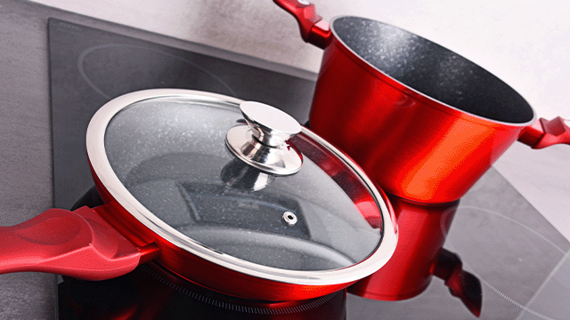 Rode pannen op een kookplaat, één met een glazen deksel. De pannen hebben zilverkleurige details en rode handvatten.
