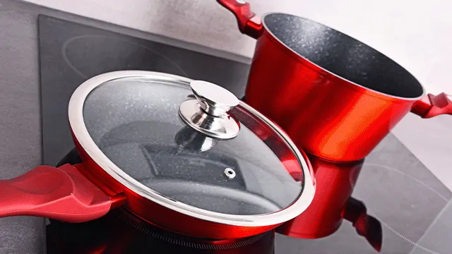 Rode pannen op een kookplaat, één met een glazen deksel. De pannen hebben zilverkleurige details en rode handvatten.