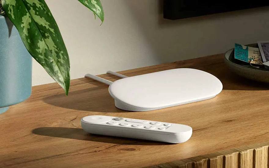 Chromecast apparaat en afstandsbediening op een houten tafel.