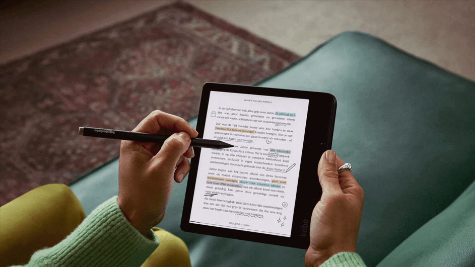 Hands hold a stylus and tablet displaying text with highlights, on a teal chair. A patterned rug is in the background.