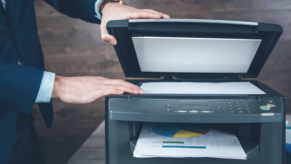 Een persoon in pak opent een printer met een grafiek eronder.