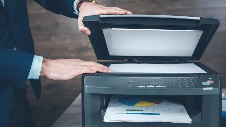 Een persoon in pak opent een printer met een grafiek eronder.