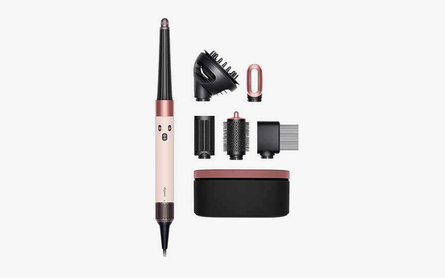 Rose gold multi styler shown with several attachments, including diffuser, round brushes and comb head, alongside a matching black and pink storage case.