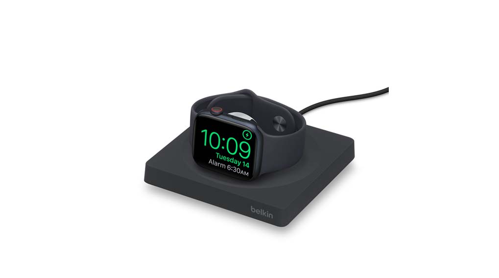Een zwarte smartwatch ligt op een zwart Belkin-oplaadstation tegen een witte achtergrond; het scherm toont 10:09.