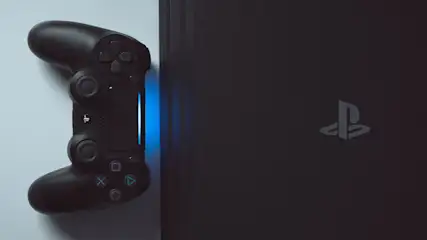 Een zwarte PlayStation-controller ligt naast een zwarte console met een blauwe lichtstreep.