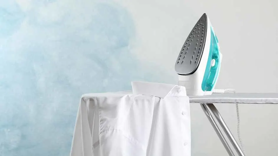 Een strijkijzer staat op een strijkplank naast een wit overhemd, tegen een blauw-witte achtergrond.