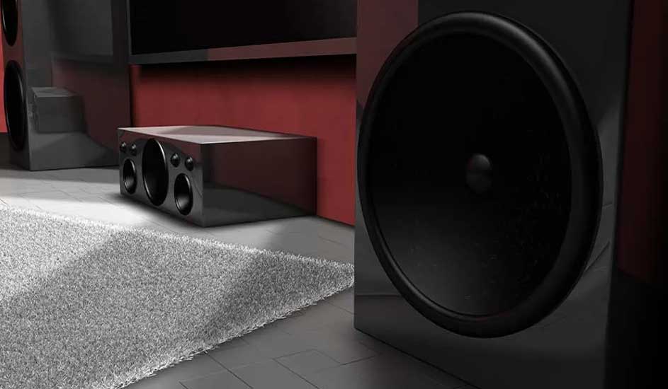 Thuisbioscoop met zwarte luidsprekers, subwoofer en rode muur. Zachte grijze tapijt op de vloer voor comfort en indrukwekkend geluid.