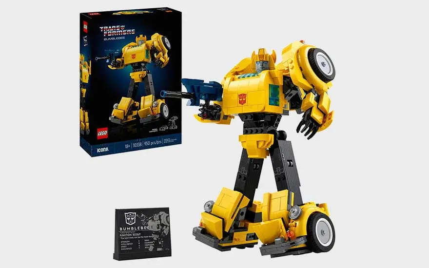 Gele LEGO Bumblebee Transformer staat naast zijn doos en displayplaat, met robotarmen, wielen en herkenbare details.