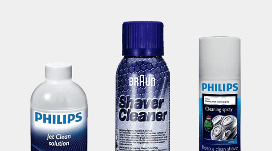 Drie flessen scheerreiniger staan op een witte achtergrond. Philips Jet Clean-oplossing en reinigingsspray, Braun scheerapparaatreiniger.