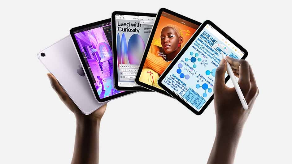 Hands hold four tablets displaying various screens, including text, graphics, and a portrait, against a white background.
