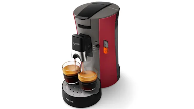 Een rood-grijze Senseo koffiemachine vult twee glazen met zwarte koffie op een zwart Philips-onderzetter.