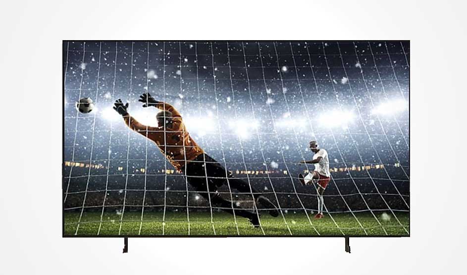 Een grote televisie toont een voetbalscène met doelman die een bal vangt in een stadion met felle lichten. Dynamische actie met groen veld en net. Uitstekende beeldkwaliteit en contrastweergave.