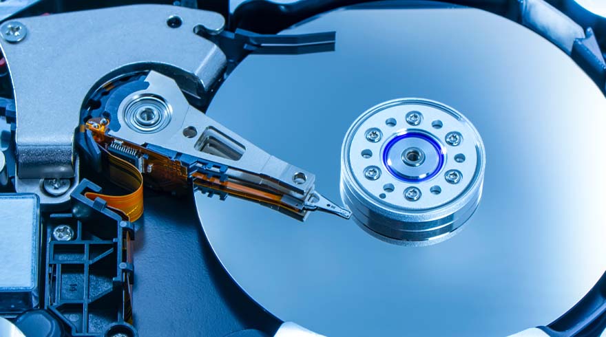 Een open harde schijf met een zilverkleurige leeskop en een ronde schijf. Zwarte en oranje details zijn zichtbaar.