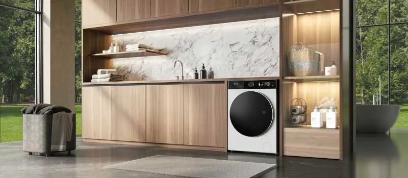 Een moderne wasruimte met houten kasten, marmeren wand, witte wasmachine, open planken en grote ramen met uitzicht op groen.