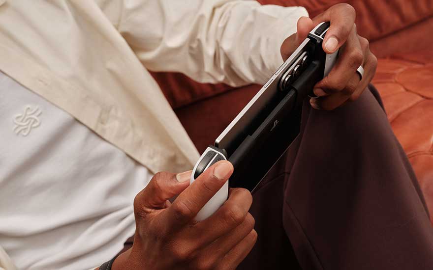 Blauwe vouwbare smartphones staan op een glazen tafel buiten, één dichtgeklapt met scherm en één rechtop met drievoudige camera.