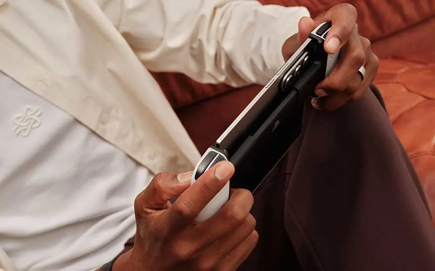 Blue foldable smartphones sit on an outdoor glass table, one closed with a cover display and one upright with triple cameras.