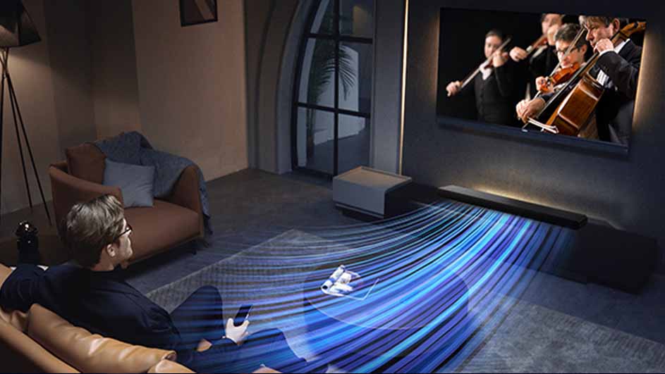 Man zit op een bank met een afstandsbediening, kijkend naar een tv met een orkest. Een soundbar staat onder de tv.