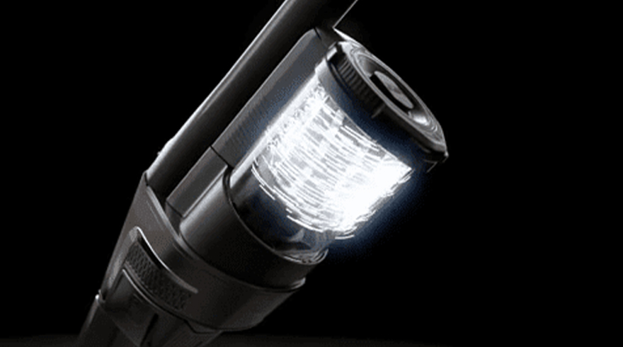 Een zwarte stofzuiger met een helder wit verlichtingselement tegen een donkere achtergrond.