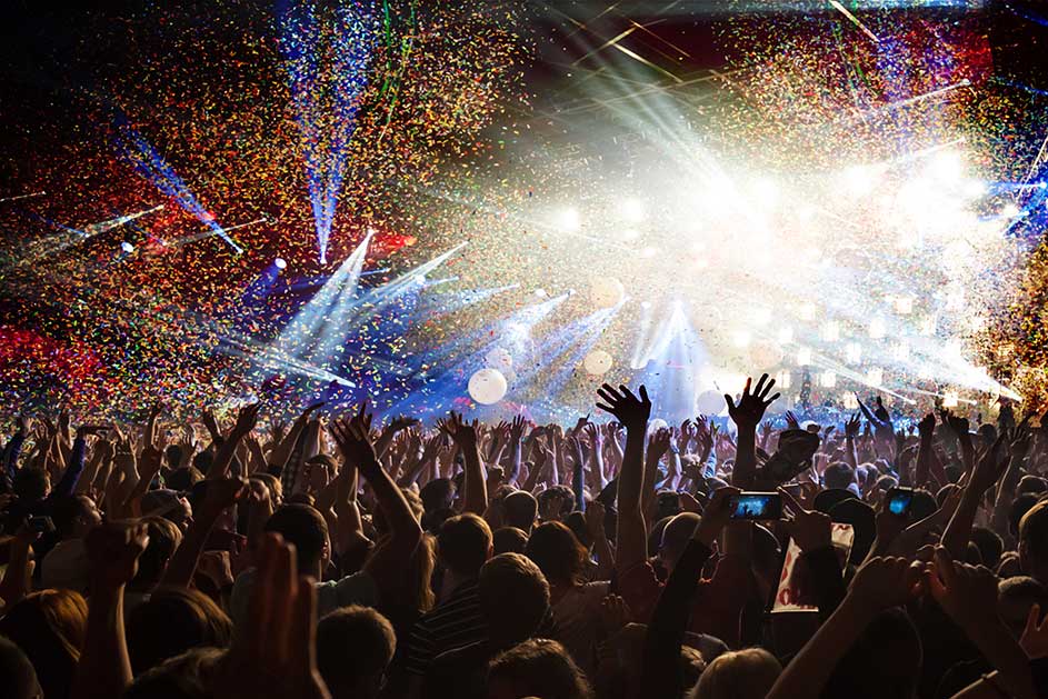 Grote menigte viert op een concert met felle lichten en confetti.
