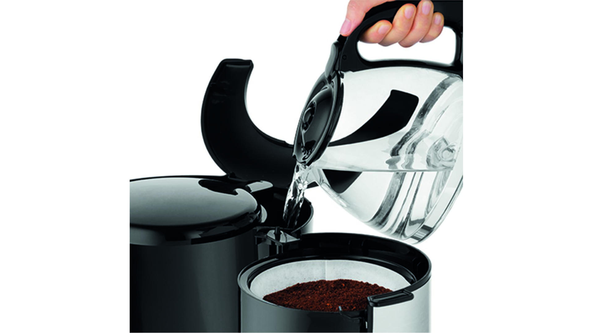 Een hand giet water uit een glazen kan in een zwart koffiezetapparaat met een wit filter en koffie.