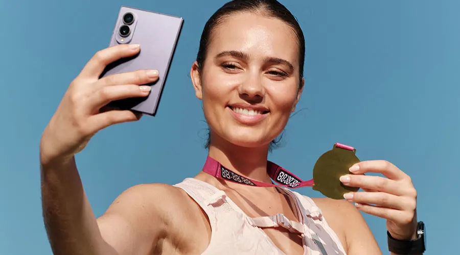 Vrouw maakt een selfie met een Samsung-smartphone en houdt een medaille vast.