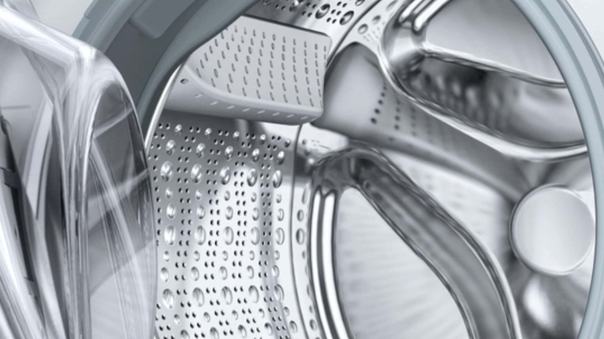 Gedetailleerd zicht op de binnenkant van een wasmachinetrommel, gemaakt van grijs metaal met perforaties.