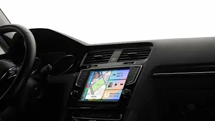 Zwart dashboard met navigatiescherm, ventilatieroosters en een deel van het stuur in een auto.