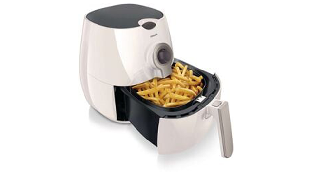 Een witte airfryer met een zwarte bovenkant en een mand vol frietjes, tegen een witte achtergrond.