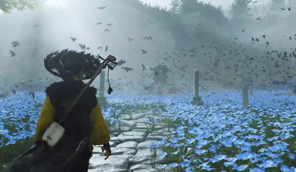 Een samoerai met rieten hoed loopt over een pad door een veld vol blauwe bloemen, omringd door vliegende zwarte vogels. Merk: Ghost of Tsushima.