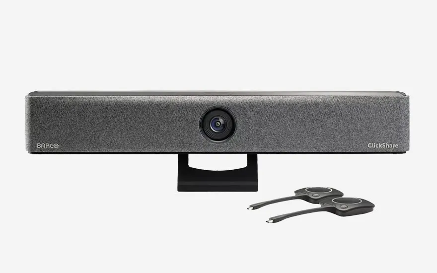 Een grijze Barco ClickShare videoconferentiecamera op zwarte standaard met twee USB-dongles voor draadloze presentaties en videovergaderingen.