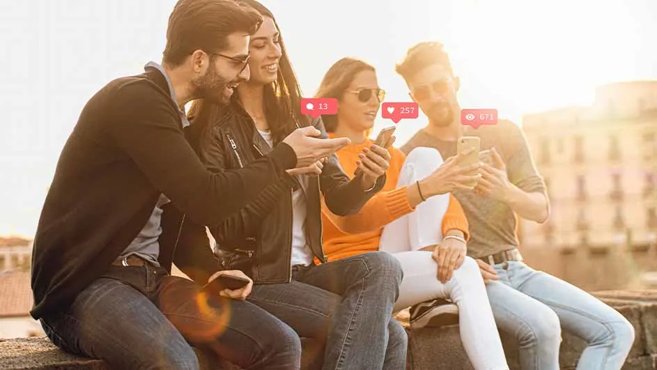 Vier mensen zitten buiten op een muur en kijken naar smartphones met meldingen. De achtergrond toont gebouwen.