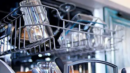 Een open vaatwasser met schone glazen, borden en bestek in een moderne keuken. Het merk is niet zichtbaar op de afbeelding.