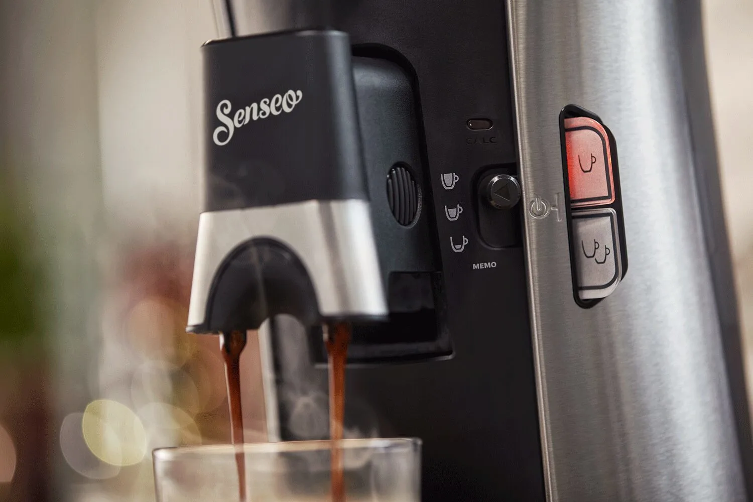 Een Senseo-koffiezetapparaat schenkt koffie in een glas, met knoppen en het Senseo-logo zichtbaar.