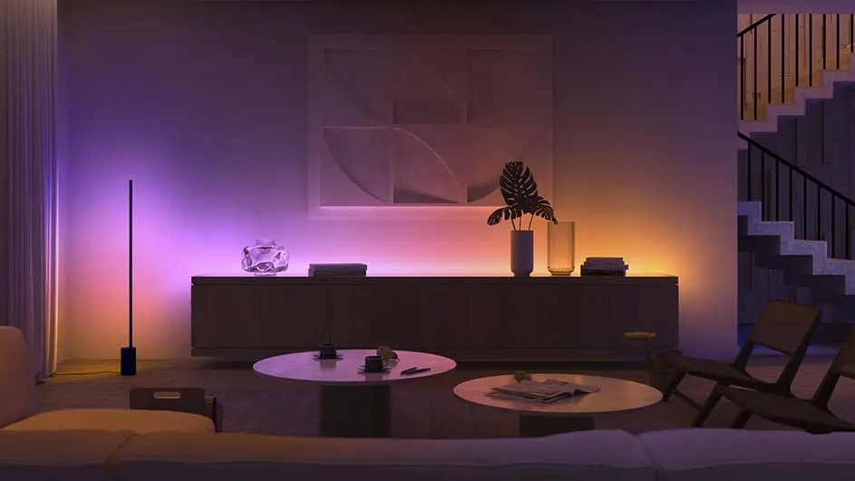 Woonkamer met kast, planten, tafels en stoelen. Trap in de achtergrond. Paars en oranje lichteffecten op de muur.