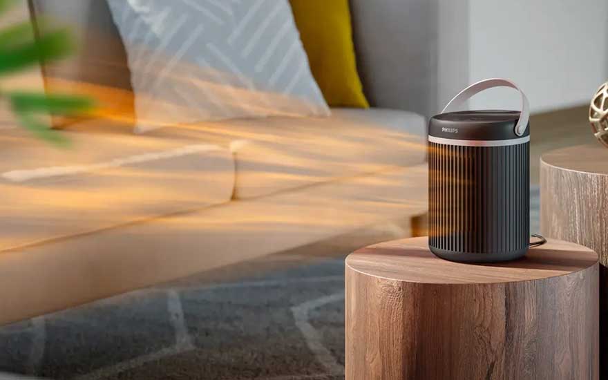 Een compacte, zwarte Philips-verwarming verspreidt warme lucht in een moderne woonkamer, zichtbaar aan stromen warmte.