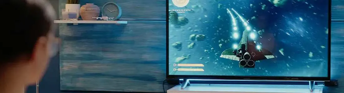 Een persoon speelt een ruimteschipspel op een tv, met een kom popcorn op een tafel.