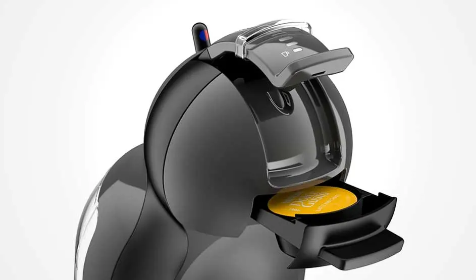 Op de afbeelding zie je een zwarte KRUPS NESCAFÉ Dolce Gusto koffiemachine met een gele koffiecapsule in de houder.