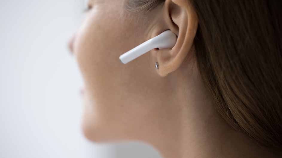 Profiel van een persoon met een wit oortje in het oor en een kleine, zilverkleurige oorbel.