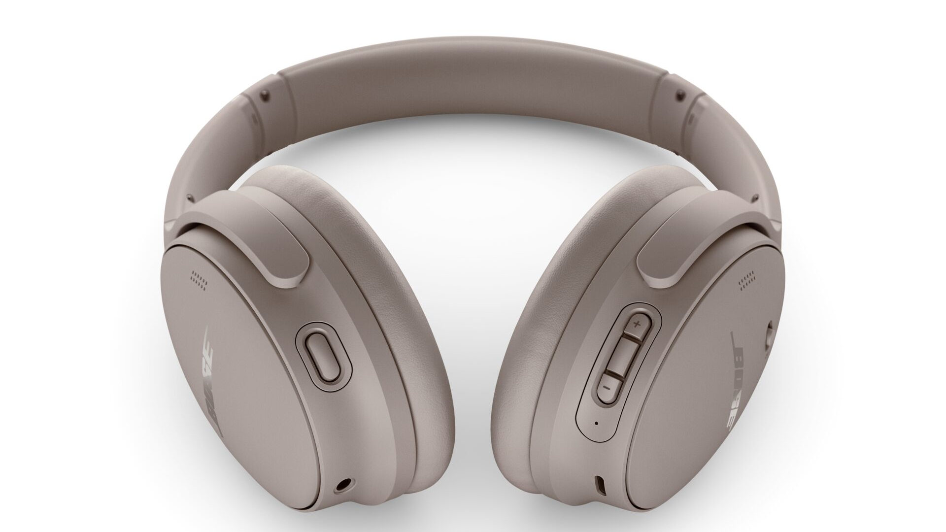 Een taupekleurige Bose hoofdtelefoon ligt op een witte achtergrond, met knoppen aan de rechterkant en een microfoonopening aan de linkerkant.