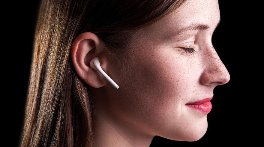 Zijaanzicht van een persoon met gesloten ogen en rode lippen, met een witte oortelefoon in het oor tegen een zwarte achtergrond.