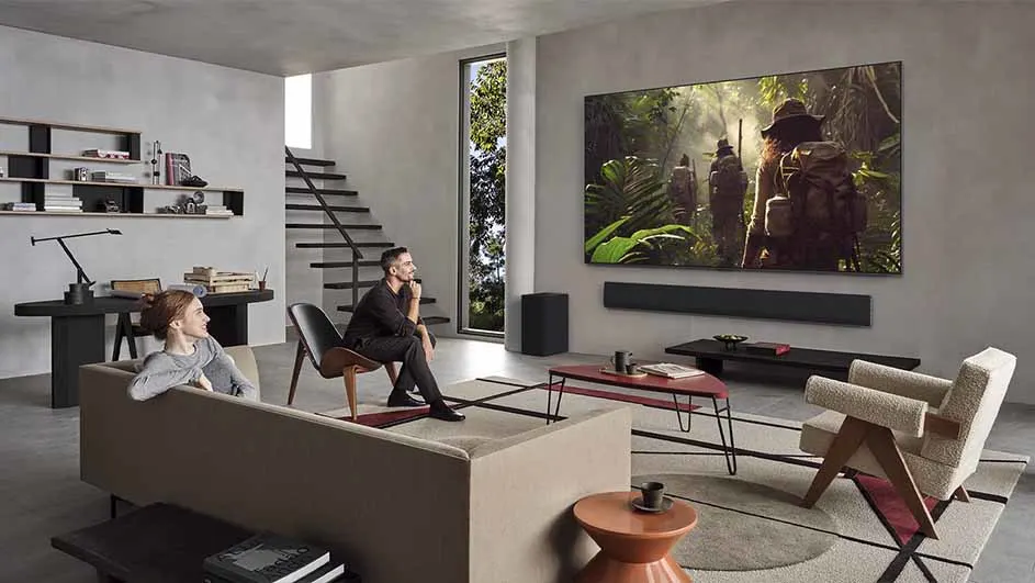 Een koppel kijkt naar een natuurdocumentaire op een grote aan de muur gemonteerde LG-televisie in een moderne woonkamer.