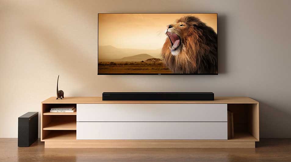 Een grote tv toont een brullende leeuw boven een houten meubel met soundbar; de kamer oogt strak, warm en modern.