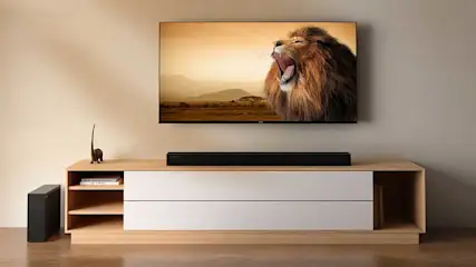 Een grote tv toont een brullende leeuw boven een houten meubel met soundbar; de kamer oogt strak, warm en modern.