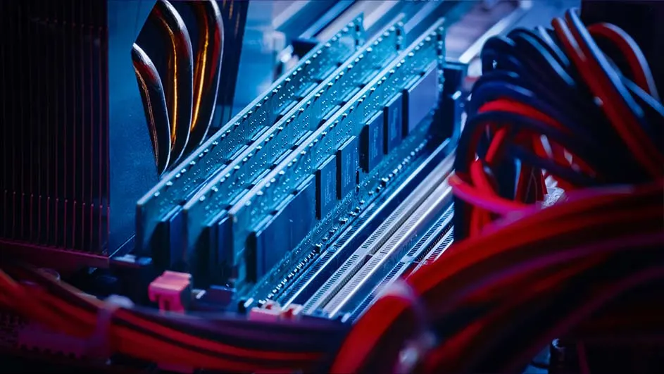 Dichtbijbeeld van computerhardware met blauwe RAM-modules, rode en zwarte kabels, en een zwart koellichaam.