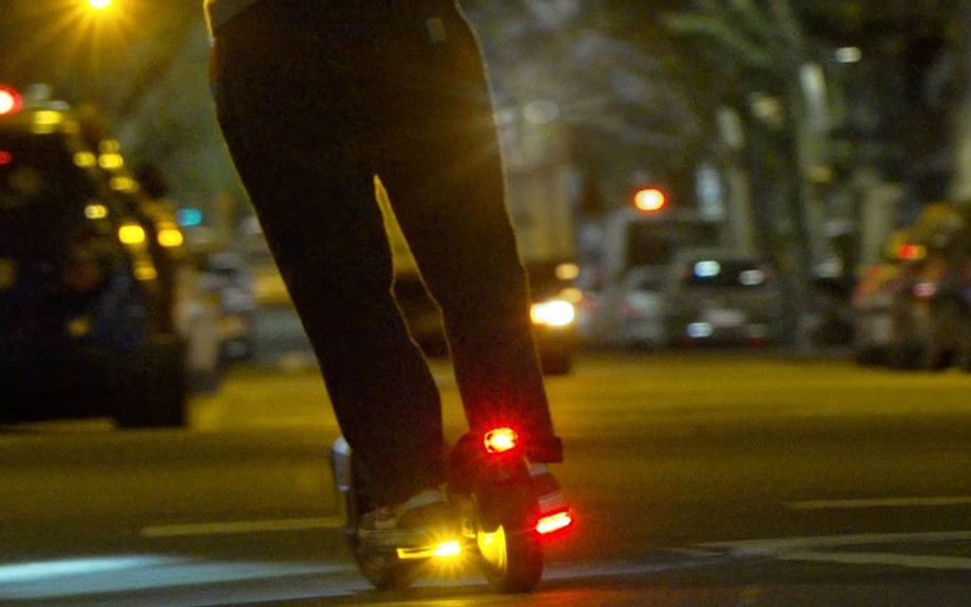 Nachtelijke straatscène met verlichte voeten op een step, rode en gele LED-lichten zorgen voor veiligheid in het donker.