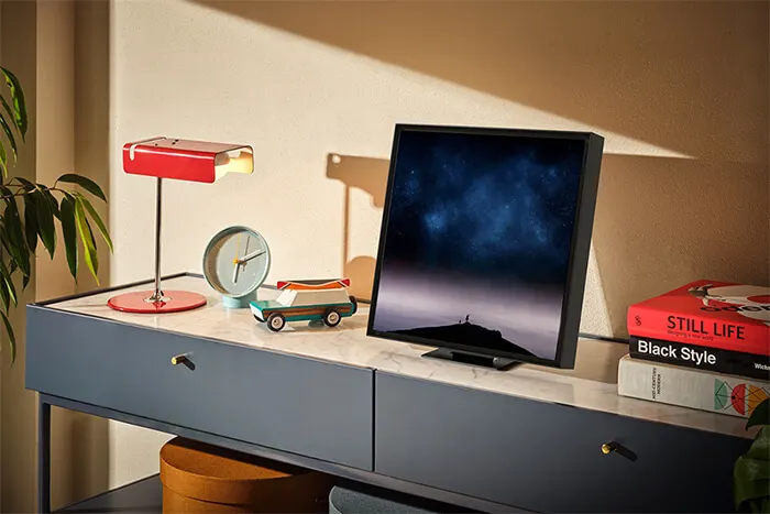 Bureau met een rode lamp, klok, speelgoedauto, monitor met een blauwe afbeelding en boeken.